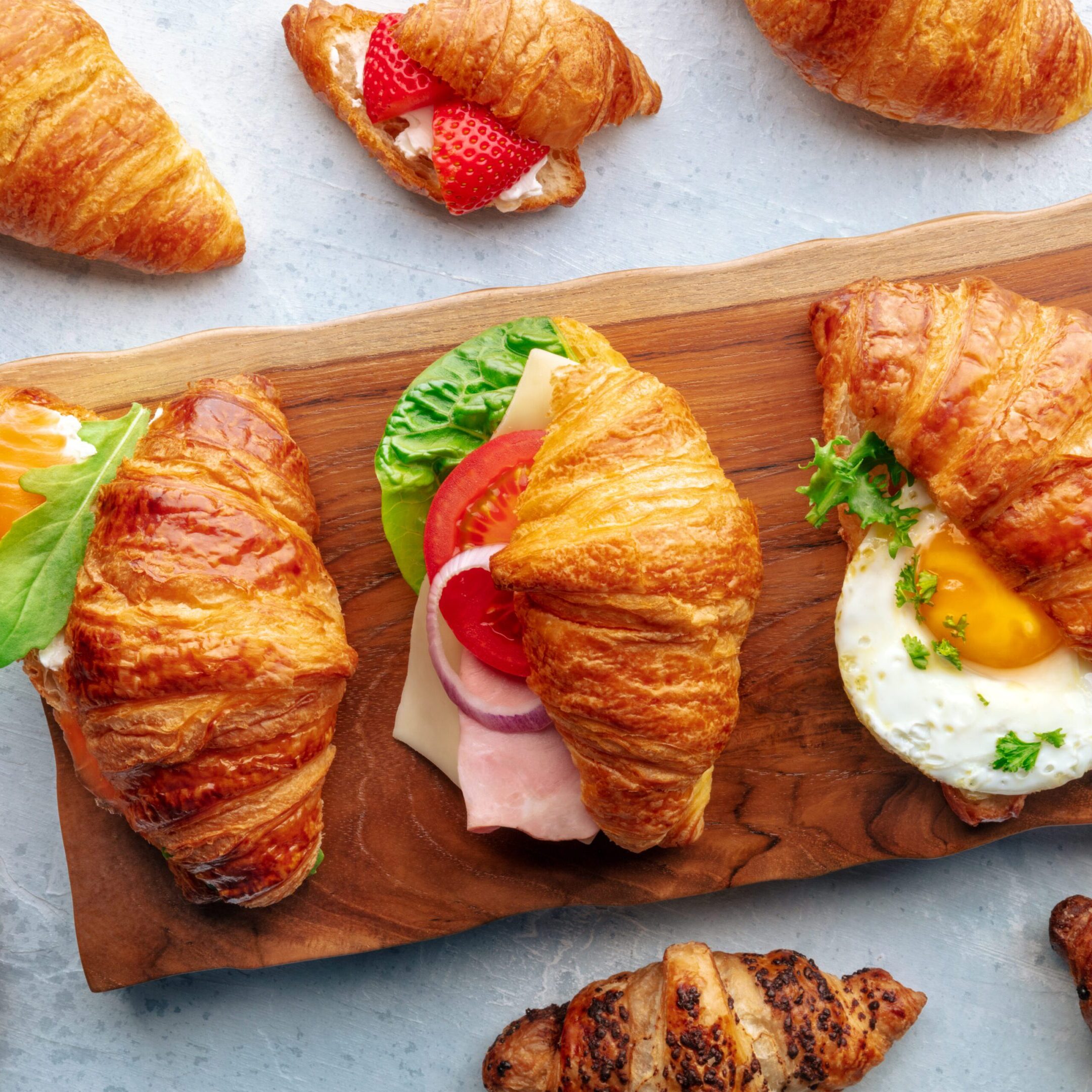 Croissant sandwich variety. Various stuffed croissants, overhead flat lay shot. Many rolls filled with ham, salmon, egg, etc